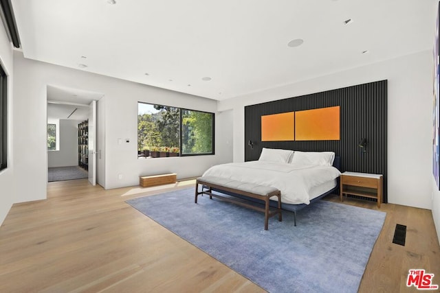 bedroom with light hardwood / wood-style floors and multiple windows