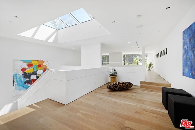 sitting room with a skylight and light hardwood / wood-style flooring