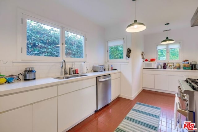 kitchen featuring backsplash, sink, appliances with stainless steel finishes, decorative light fixtures, and white cabinetry