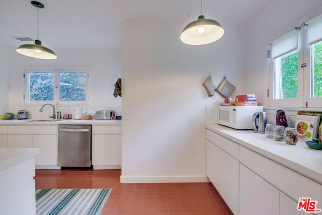 kitchen featuring white cabinets, sink, stainless steel dishwasher, light tile patterned floors, and decorative light fixtures