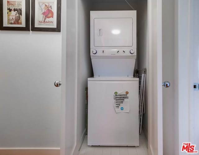 clothes washing area with light tile patterned floors and stacked washer and clothes dryer