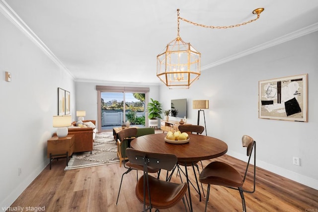 dining room with crown molding, hardwood / wood-style flooring, and an inviting chandelier