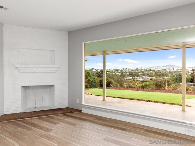 unfurnished living room with hardwood / wood-style flooring, a fireplace, and a mountain view