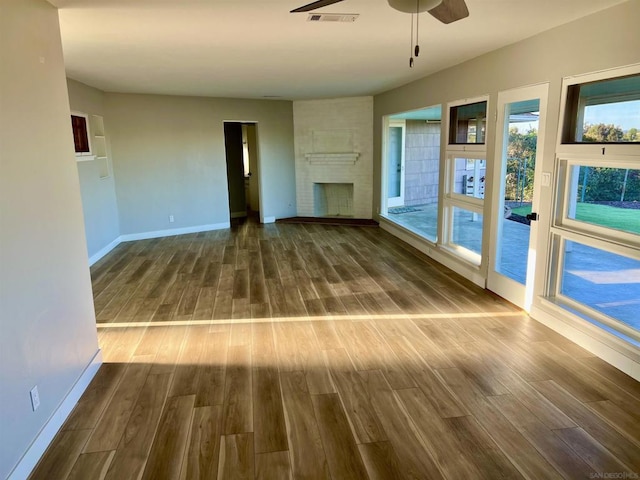 unfurnished living room featuring ceiling fan, wood-type flooring, and a fireplace