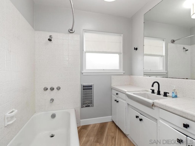 bathroom featuring vanity, hardwood / wood-style floors, heating unit, and tiled shower / bath