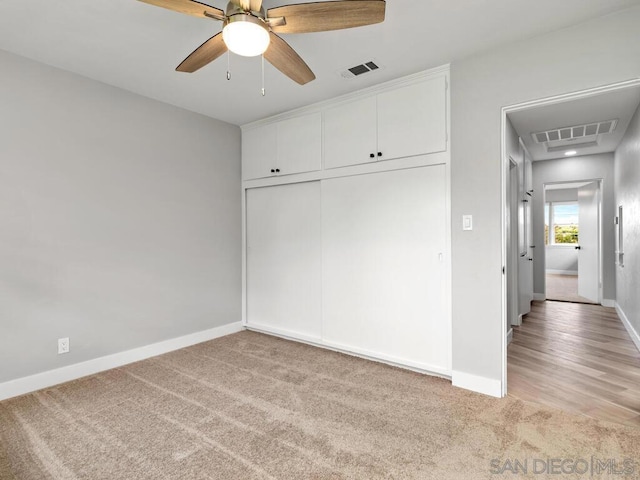 unfurnished bedroom with light carpet, ceiling fan, and a closet