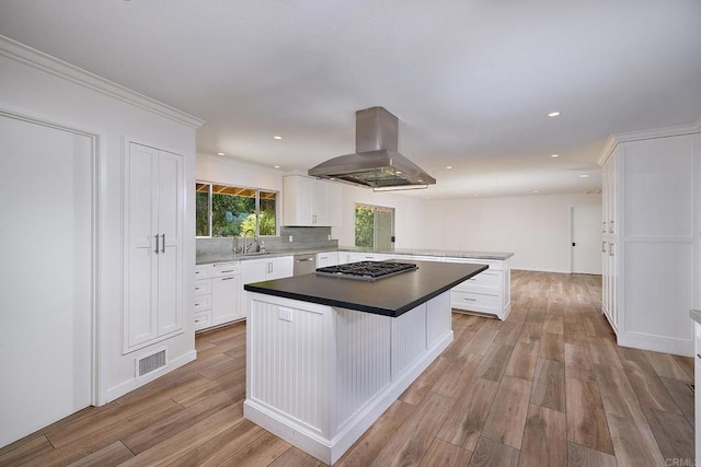 kitchen featuring sink, light hardwood / wood-style flooring, a kitchen island, island range hood, and white cabinetry