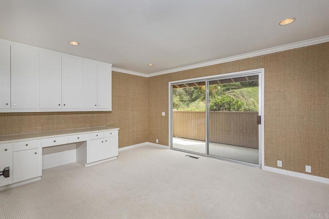 unfurnished office with crown molding, light colored carpet, and built in desk