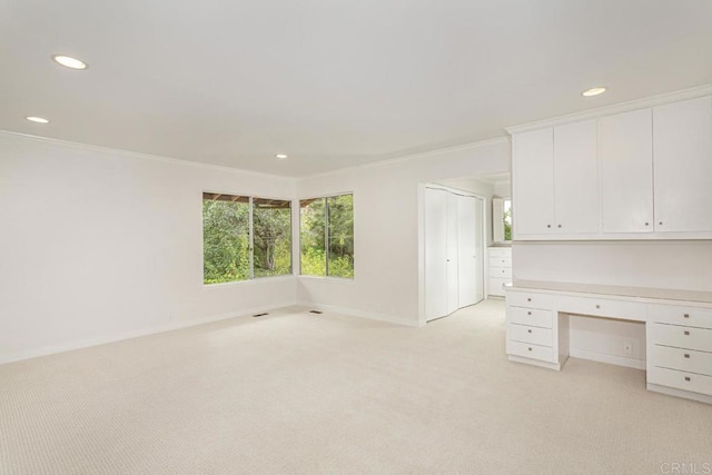 unfurnished office with built in desk, light colored carpet, and ornamental molding