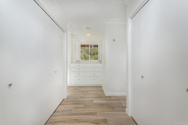 hall with crown molding and light hardwood / wood-style flooring