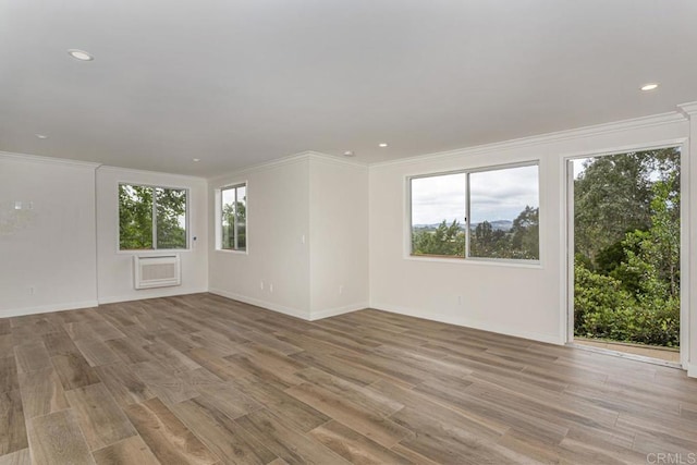 spare room with light hardwood / wood-style flooring, a wall mounted air conditioner, and ornamental molding