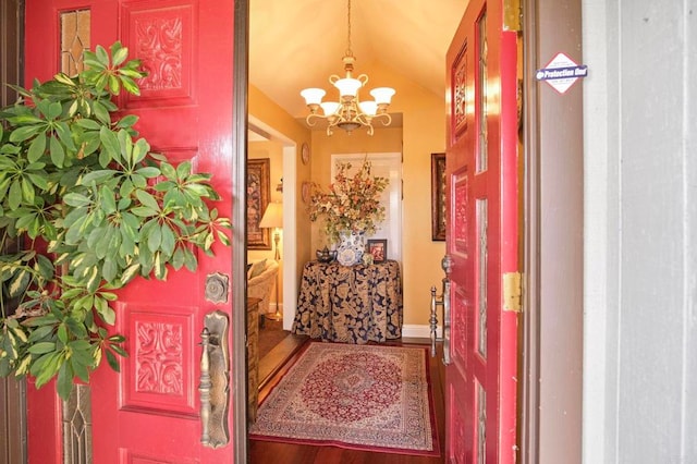 foyer entrance featuring hardwood / wood-style flooring, lofted ceiling, and an inviting chandelier