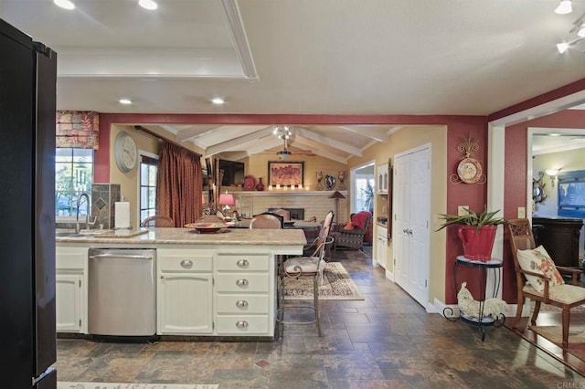 kitchen featuring ceiling fan, dishwasher, lofted ceiling with beams, kitchen peninsula, and a kitchen bar