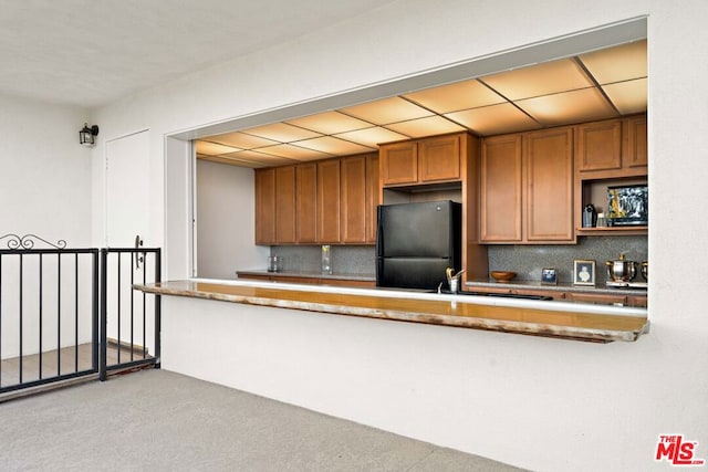 kitchen featuring backsplash and black refrigerator