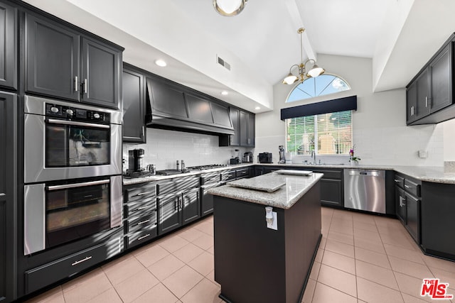 kitchen featuring a center island, premium range hood, light tile patterned floors, appliances with stainless steel finishes, and a notable chandelier