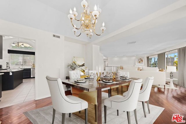 dining space with hardwood / wood-style flooring, sink, and an inviting chandelier