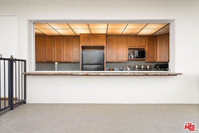 kitchen featuring tasteful backsplash, black microwave, and fridge