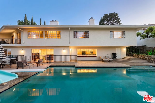 back house at dusk with a patio and a fenced in pool