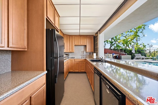 kitchen featuring dishwasher, tasteful backsplash, black fridge, and sink