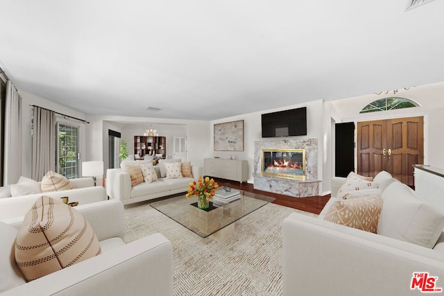 living room featuring wood-type flooring, a notable chandelier, and a premium fireplace