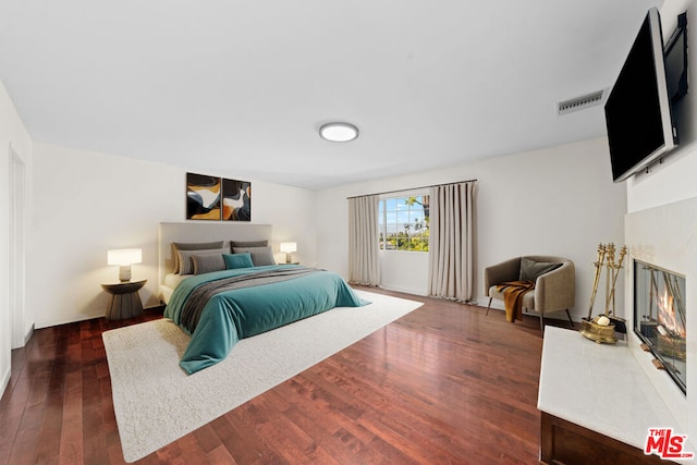 bedroom with a premium fireplace and dark hardwood / wood-style flooring