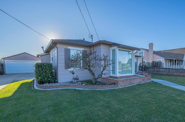 exterior space featuring a lawn, a garage, and an outbuilding