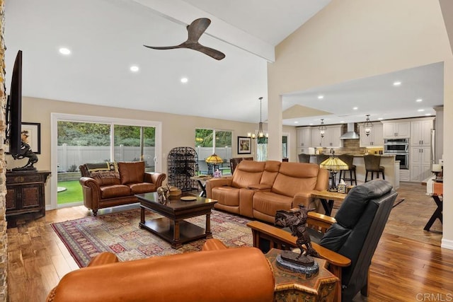 living room featuring ceiling fan with notable chandelier, high vaulted ceiling, and light wood-type flooring