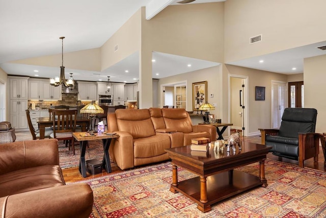 living room featuring high vaulted ceiling, a chandelier, and light hardwood / wood-style floors