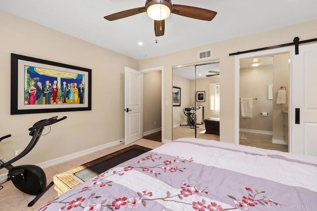 bedroom with a barn door, connected bathroom, ceiling fan, and a closet