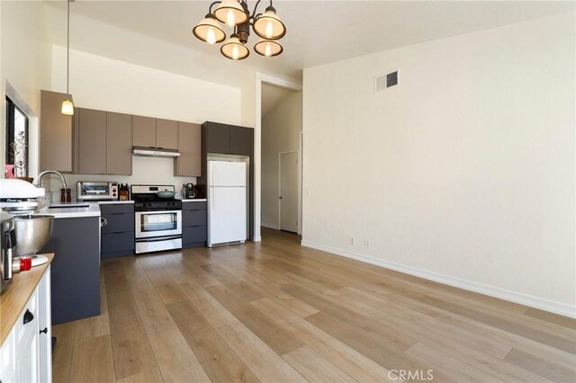 kitchen featuring white refrigerator, decorative light fixtures, light hardwood / wood-style floors, a notable chandelier, and stainless steel range with gas stovetop