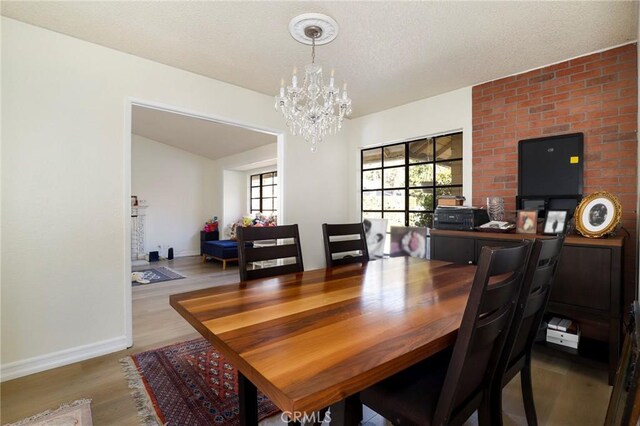 dining room with hardwood / wood-style floors, a textured ceiling, a chandelier, and plenty of natural light