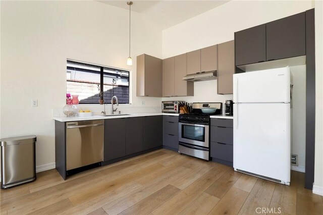 kitchen featuring sink, light wood-type flooring, pendant lighting, and appliances with stainless steel finishes