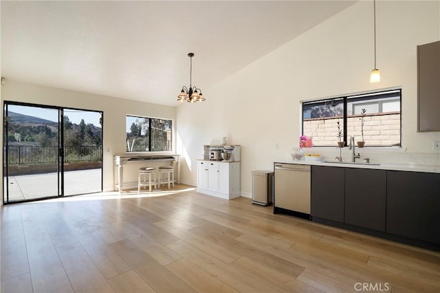 kitchen featuring stainless steel dishwasher, an inviting chandelier, sink, and hanging light fixtures