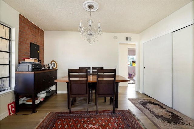 dining area featuring hardwood / wood-style flooring, an inviting chandelier, and a textured ceiling