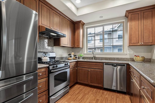 kitchen with appliances with stainless steel finishes, sink, and light wood-type flooring