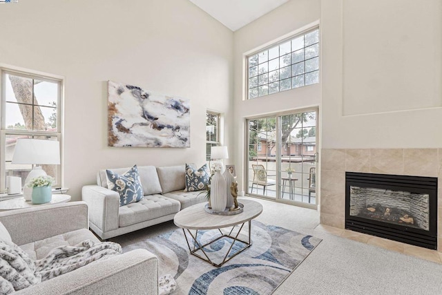 living room featuring a towering ceiling, a fireplace, and carpet floors