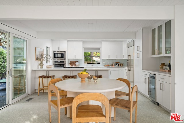 kitchen with built in appliances, tasteful backsplash, white cabinetry, beam ceiling, and beverage cooler