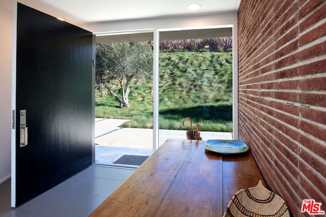 entryway featuring light tile patterned floors and brick wall