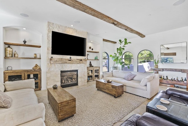 living room with a stone fireplace and beamed ceiling