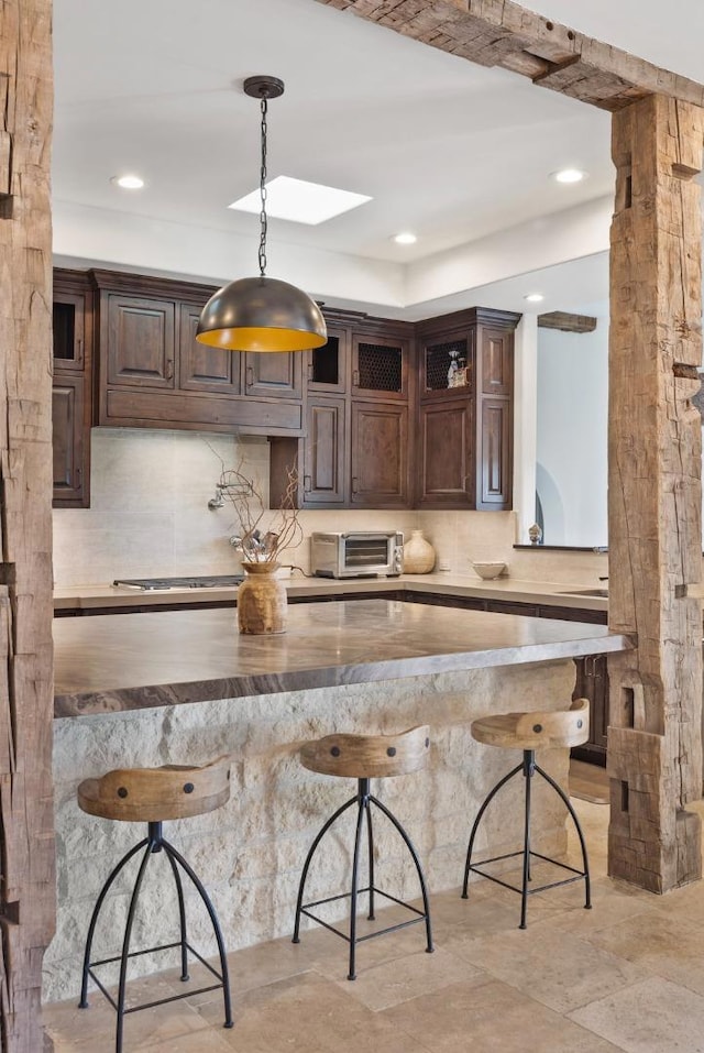 kitchen with hanging light fixtures, dark brown cabinetry, a skylight, and a breakfast bar area