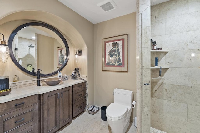 bathroom featuring toilet, vanity, and a tile shower