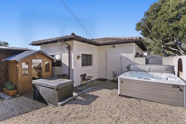 rear view of property with a hot tub and a patio area