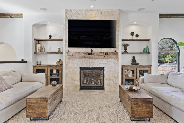 living room featuring built in features and a stone fireplace