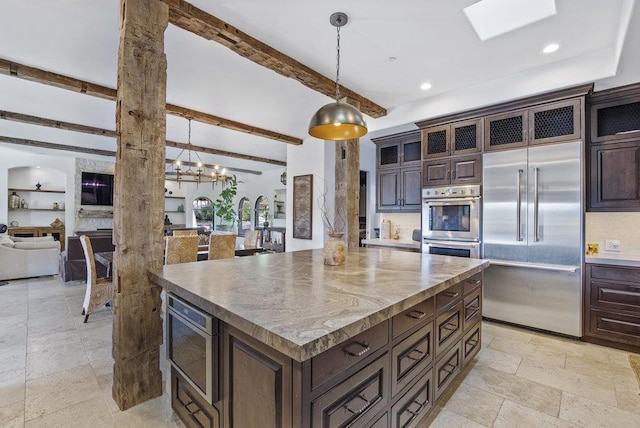 kitchen with dark brown cabinetry, a kitchen island, decorative light fixtures, built in appliances, and beam ceiling