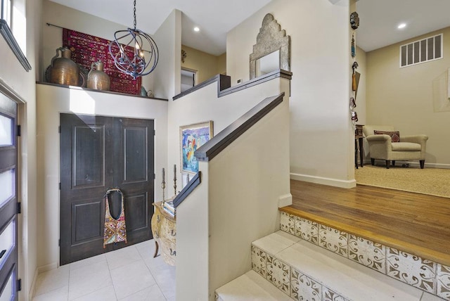 foyer with light tile patterned floors, a towering ceiling, and an inviting chandelier