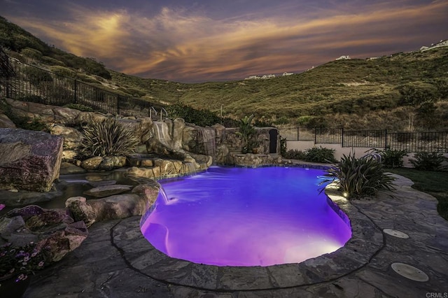 pool at dusk with pool water feature and a mountain view