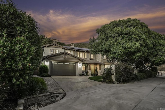 view of front of property with a chimney, stucco siding, concrete driveway, a garage, and roof mounted solar panels