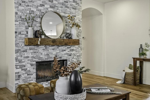 living area with a stone fireplace, wood finished floors, and baseboards