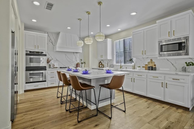 kitchen featuring white cabinetry, custom range hood, and stainless steel appliances