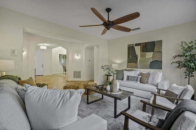 living area featuring visible vents, arched walkways, baseboards, and light wood-style flooring